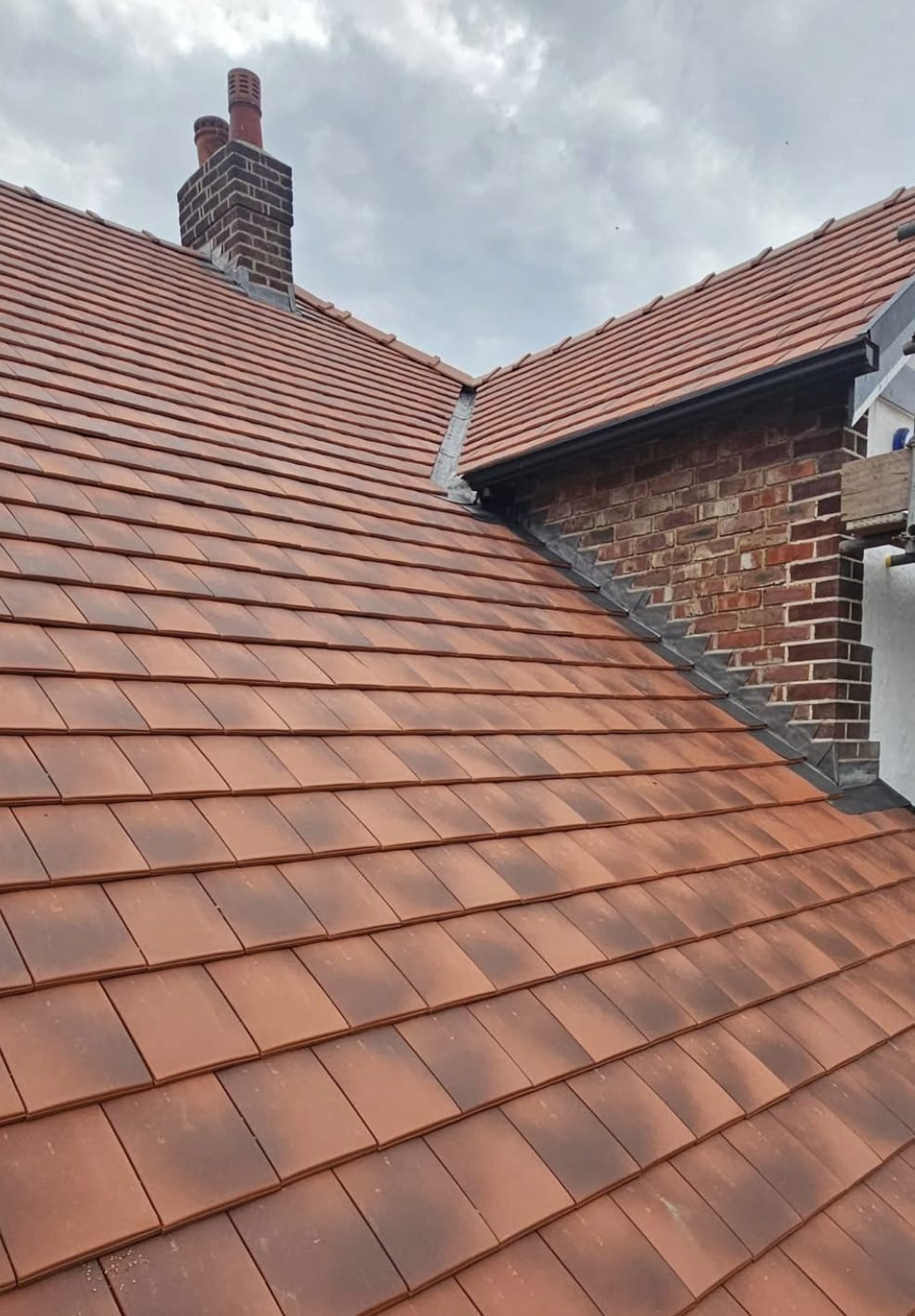 Clay plain tile roof with stepped lead flashing against brickwork