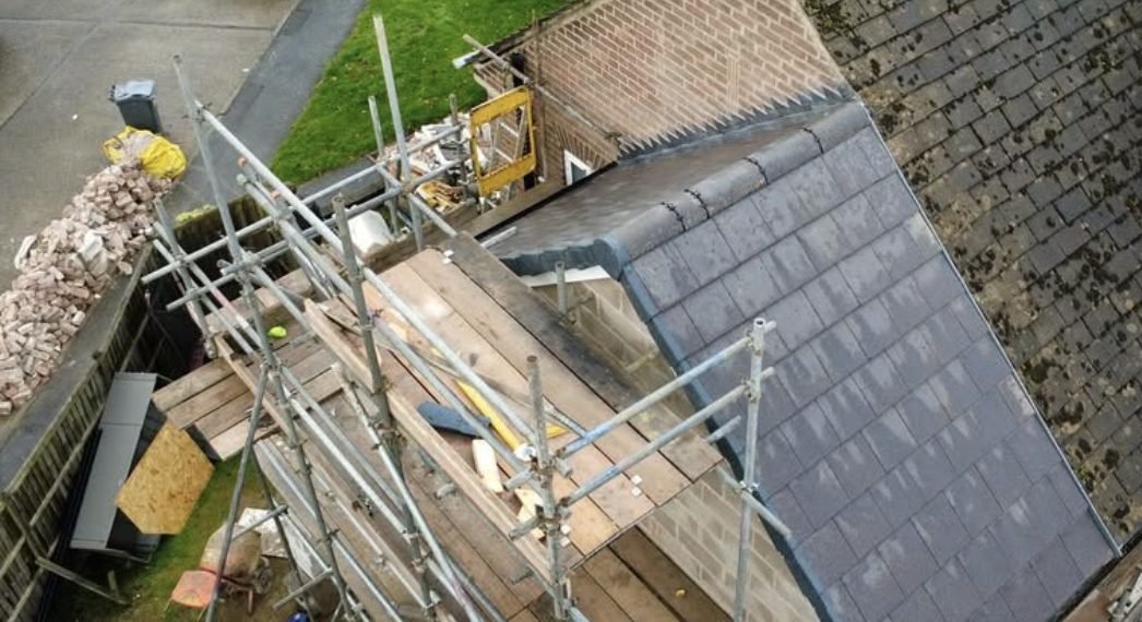 Extension roof from above with new tiles and scaffold boards alongside