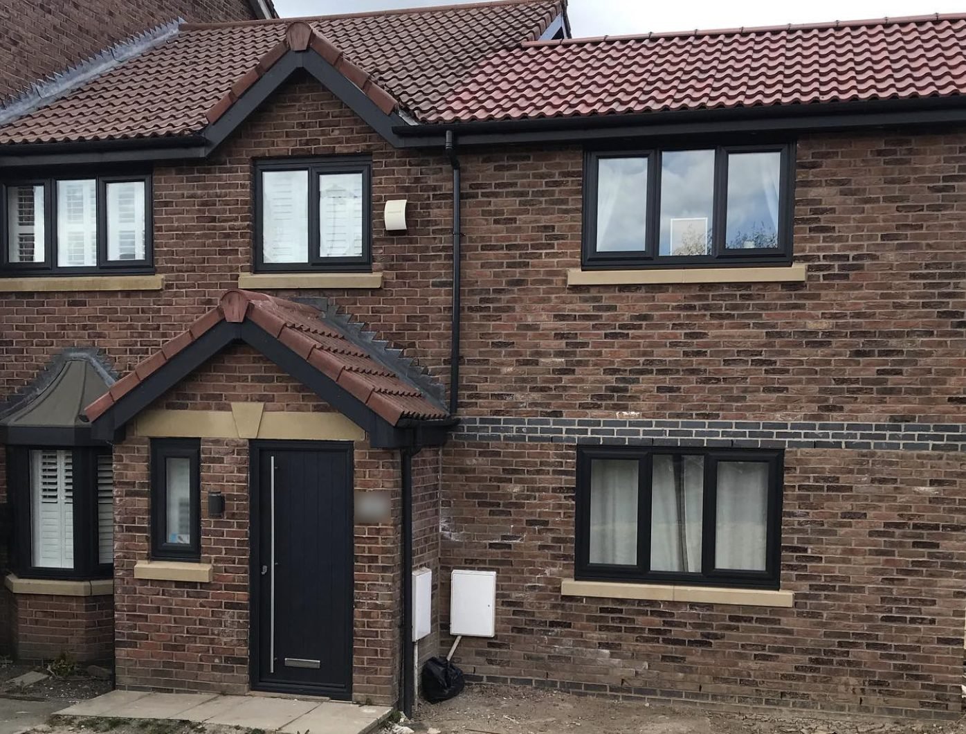 Red tiled porch and main roof with black fascias and guttering